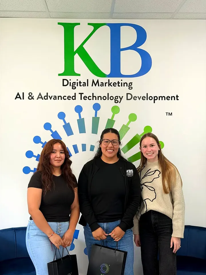 Clients and the K Business Solutions Inc. team in front of the KB logo wall at our Cypress, Texas office