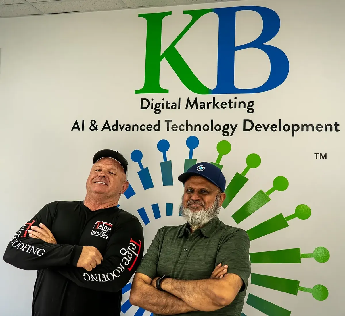 Clients and the K Business Solutions Inc. team in front of the KB logo wall at our Cypress, Texas office