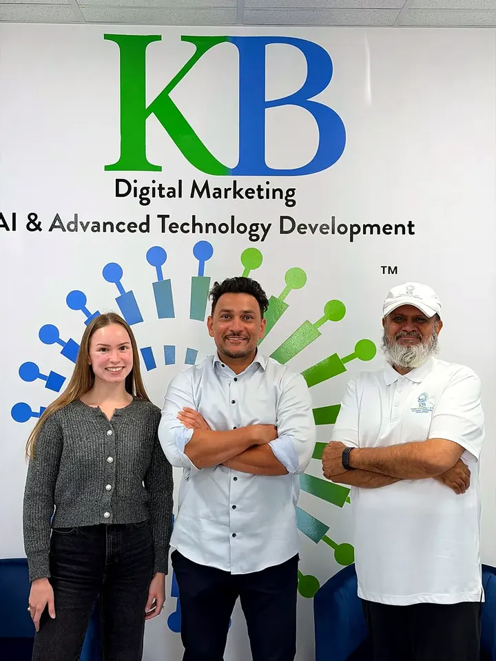 Clients and the K Business Solutions Inc. team in front of the KB logo wall at our Cypress, Texas office
