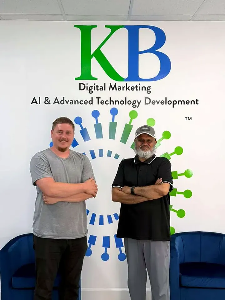 Clients and the K Business Solutions Inc. team in front of the KB logo wall at our Cypress, Texas office